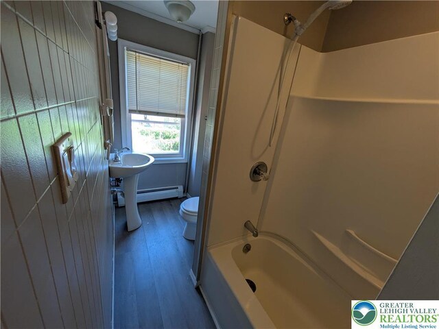 bathroom with a baseboard radiator, wood finished floors, toilet, and shower / washtub combination