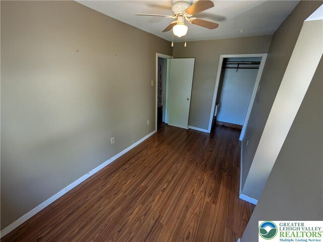 unfurnished bedroom with baseboards, a ceiling fan, dark wood-style flooring, and a closet