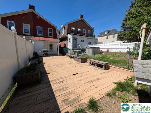 wooden terrace with a fenced backyard and grilling area