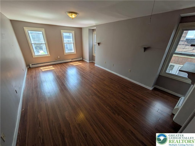 spare room featuring wood finished floors, baseboards, and a baseboard heating unit