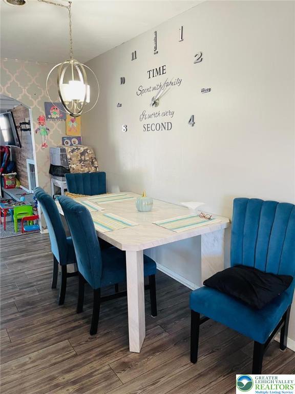 dining room featuring baseboards, wallpapered walls, a notable chandelier, and wood finished floors