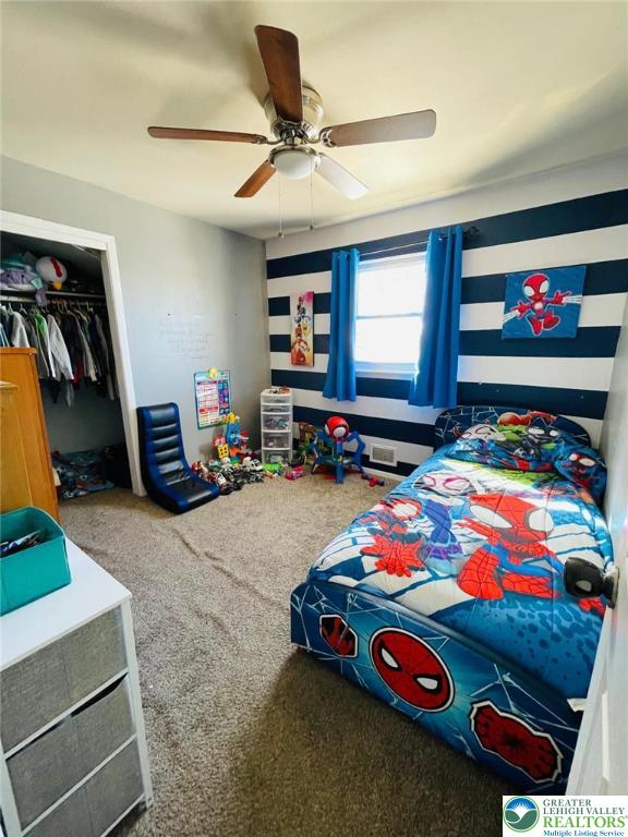 bedroom featuring carpet flooring, ceiling fan, visible vents, and a closet