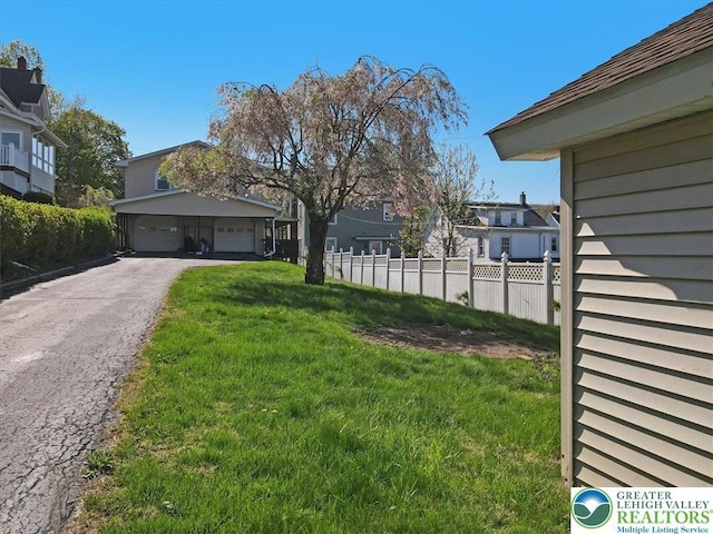 view of yard featuring fence, a residential view, and a garage