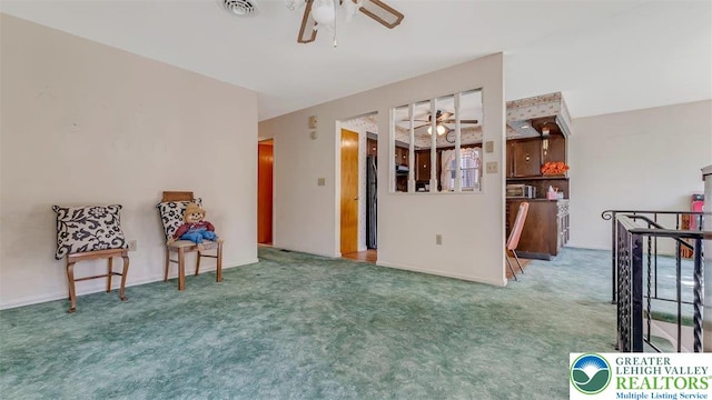 interior space featuring carpet flooring, ceiling fan, visible vents, and an upstairs landing