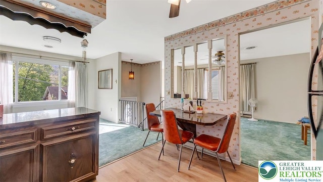 dining space with light wood-type flooring, ceiling fan, and wallpapered walls