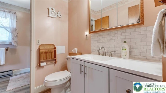 bathroom featuring vanity, wood finished floors, toilet, a baseboard heating unit, and backsplash