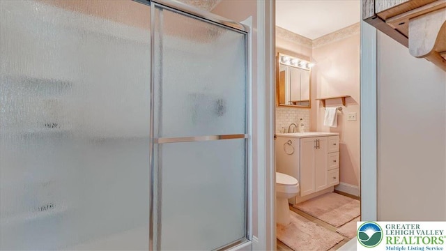 bathroom featuring vanity, toilet, tasteful backsplash, and a stall shower