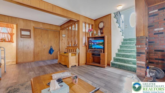 living area featuring wood walls, stairs, and wood finished floors