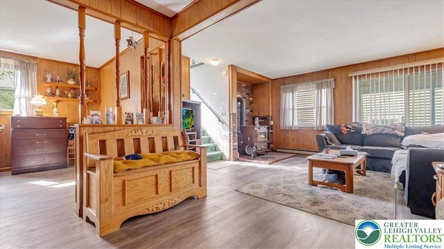 living room with wooden walls, a baseboard radiator, stairs, and wood finished floors