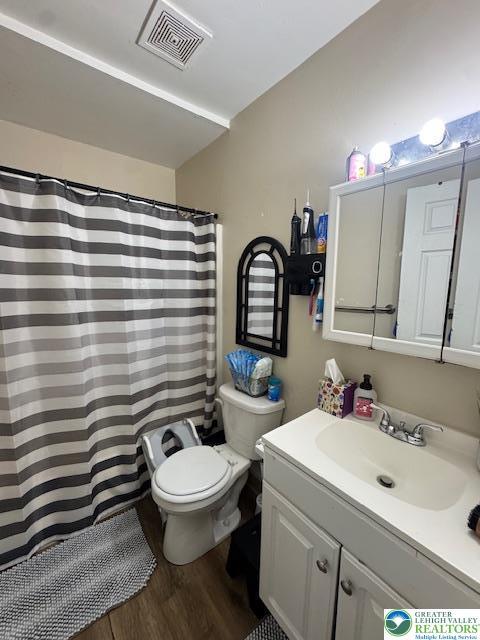 full bathroom with vanity, toilet, a shower with shower curtain, wood finished floors, and visible vents