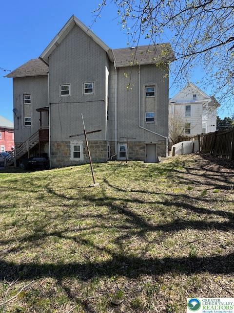 back of property with a yard and fence
