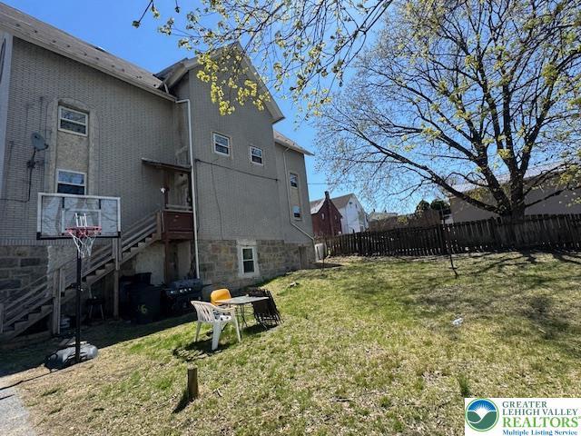 exterior space featuring fence, stairs, and a yard