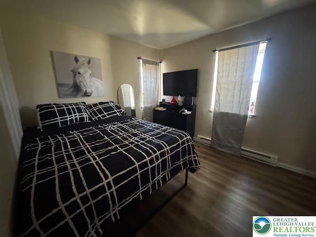 bedroom with baseboards, wood finished floors, and baseboard heating