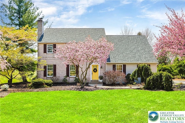 view of front of house featuring a shingled roof, a chimney, and a front lawn