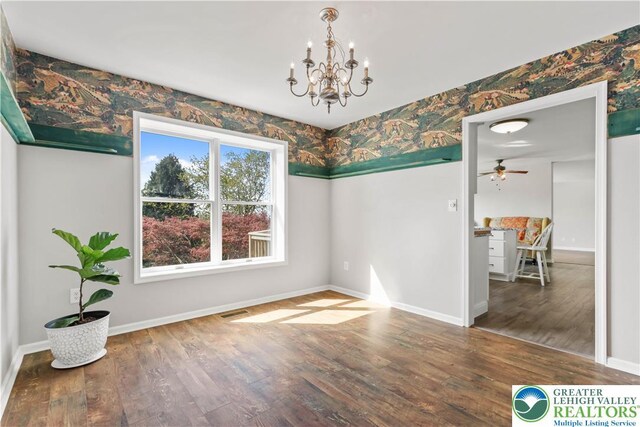 unfurnished dining area featuring baseboards, wood finished floors, visible vents, and wallpapered walls