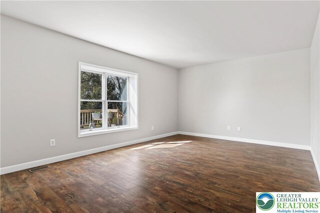 unfurnished room with baseboards, visible vents, and hardwood / wood-style floors