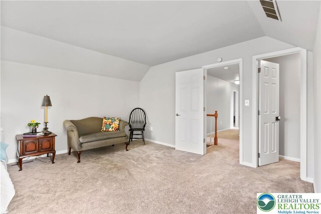 living area with baseboards, light carpet, vaulted ceiling, and visible vents