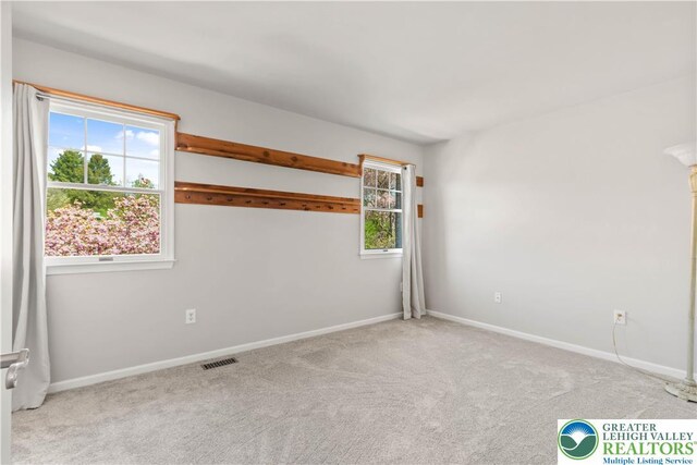 carpeted empty room featuring baseboards and visible vents