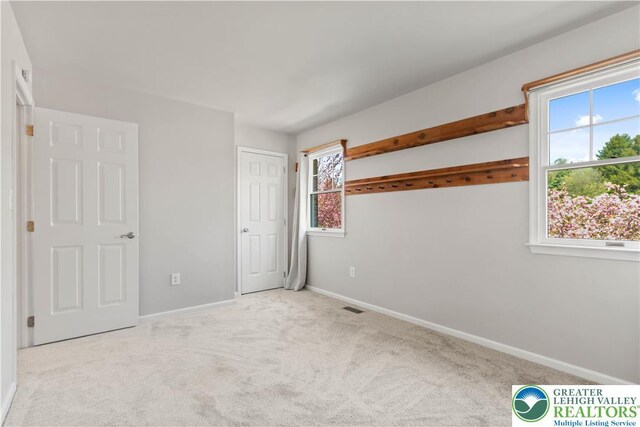unfurnished bedroom featuring baseboards, carpet flooring, and visible vents
