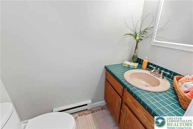 half bathroom with vanity, a baseboard radiator, and toilet