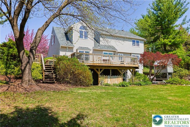 rear view of property featuring stairway, a deck, a shingled roof, and a lawn