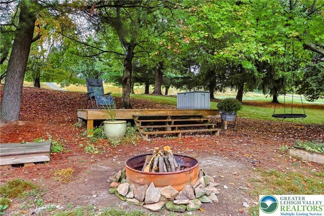 view of property's community with an outdoor structure, a shed, and an outdoor fire pit