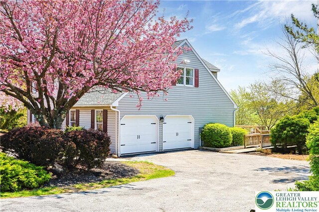 view of property exterior featuring an attached garage and driveway