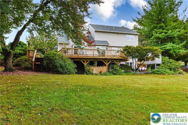 back of property with a lawn, a deck, and stairs