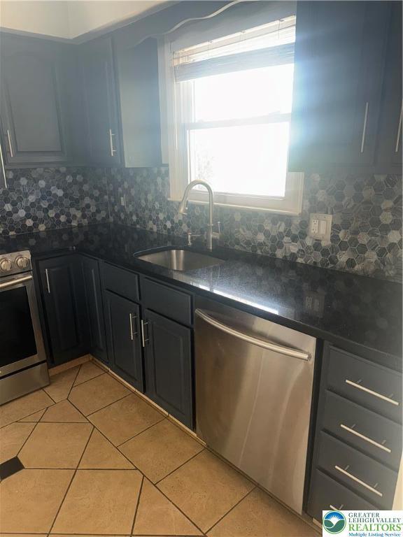 kitchen with a sink, dark countertops, stainless steel appliances, and light tile patterned flooring