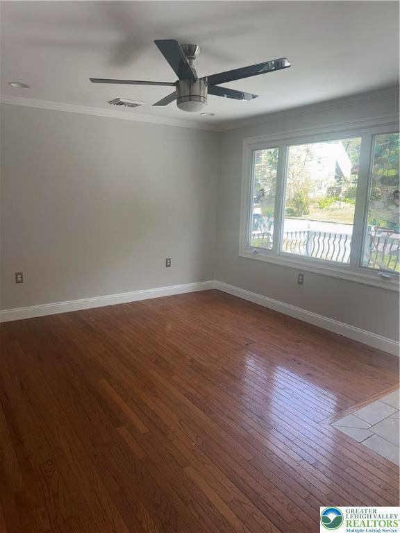 unfurnished room featuring visible vents, crown molding, hardwood / wood-style floors, baseboards, and ceiling fan