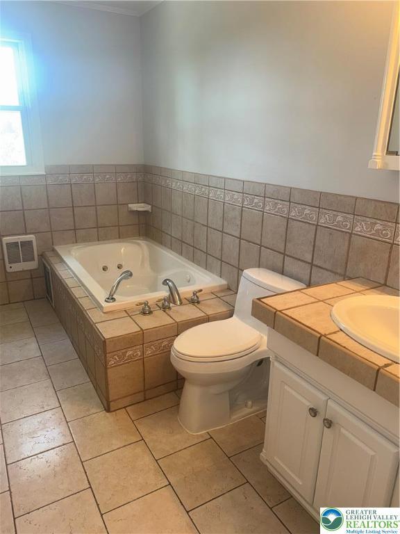 full bathroom featuring tile patterned flooring, vanity, toilet, tile walls, and a whirlpool tub