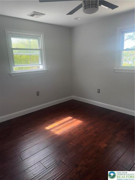 empty room with ceiling fan, dark wood-style flooring, and a wealth of natural light