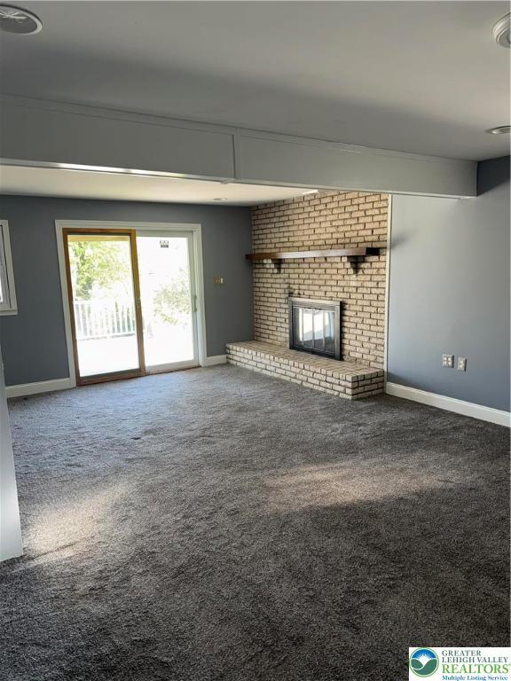 unfurnished living room with baseboards, carpet flooring, and a brick fireplace