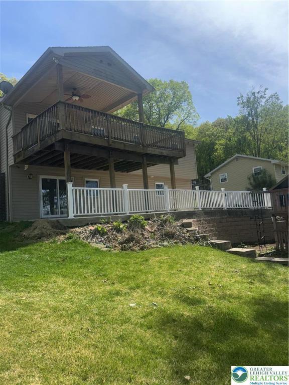 rear view of property with a lawn, a ceiling fan, and a wooden deck