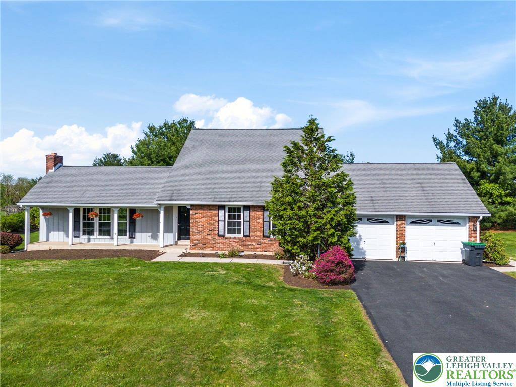 view of front of home featuring a garage, a front lawn, a chimney, brick siding, and driveway
