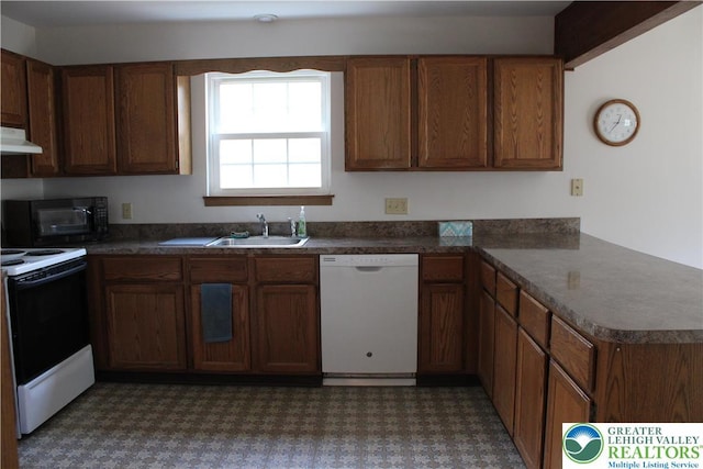 95 Piney Woods Dr, Penn Forest Township, PA 18229 - kitchen with dark countertops, a sink, a peninsula, under cabinet range hood, and white appliances