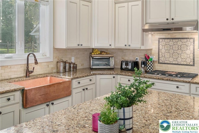 4164 Tank Farm Rd, Upper Milford Twp, PA 18049 - kitchen featuring under cabinet range hood, stainless steel gas cooktop, a sink, and tasteful backsplash