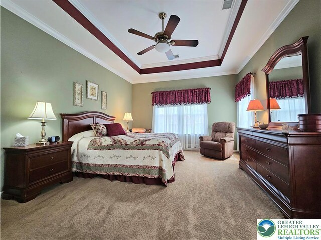 carpeted bedroom with crown molding, a ceiling fan, and a tray ceiling