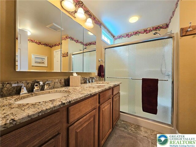 bathroom featuring visible vents, a sink, a stall shower, and double vanity