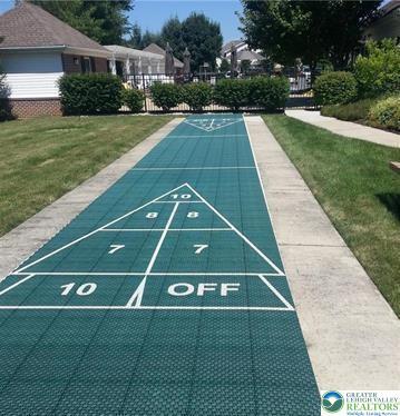 view of property's community with a lawn, uncovered parking, and shuffleboard
