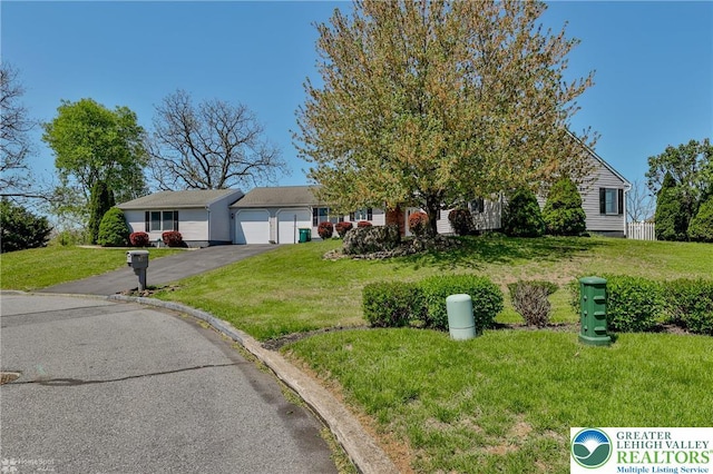 view of front of house featuring an attached garage, a front lawn, and aphalt driveway