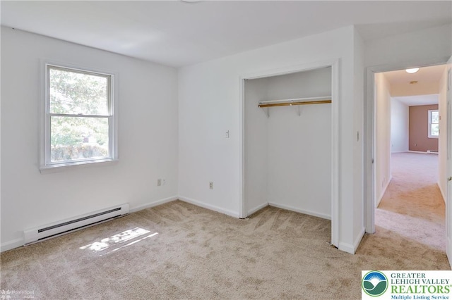 unfurnished bedroom featuring carpet floors, baseboards, baseboard heating, and a closet