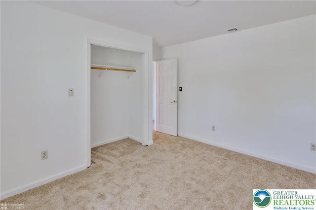 unfurnished bedroom featuring visible vents, carpet, baseboards, and a closet