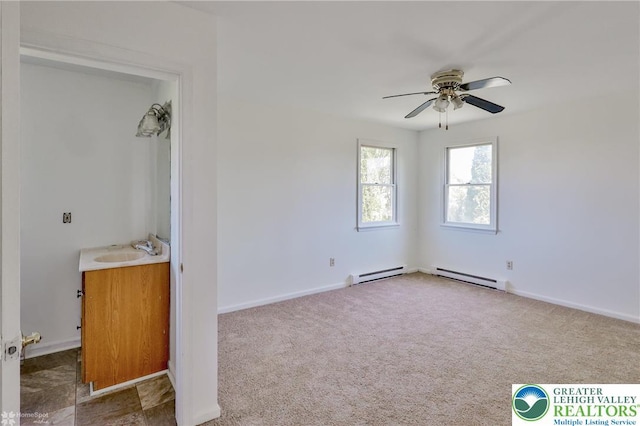 unfurnished bedroom featuring carpet flooring, baseboards, a sink, and baseboard heating