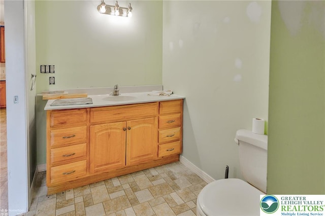 bathroom featuring baseboards, toilet, and vanity