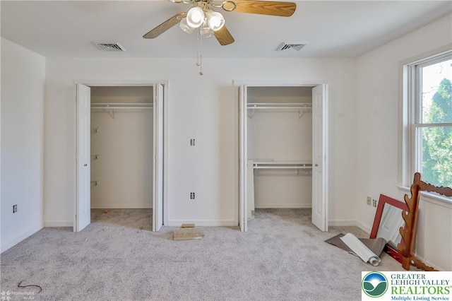 unfurnished bedroom with multiple closets, baseboards, carpet floors, and visible vents