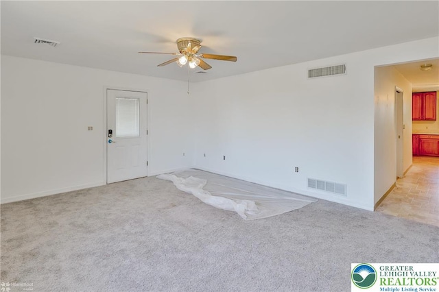 spare room with ceiling fan, visible vents, light carpet, and baseboards