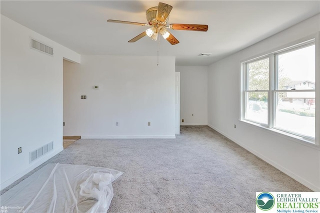 empty room with visible vents, ceiling fan, and light colored carpet