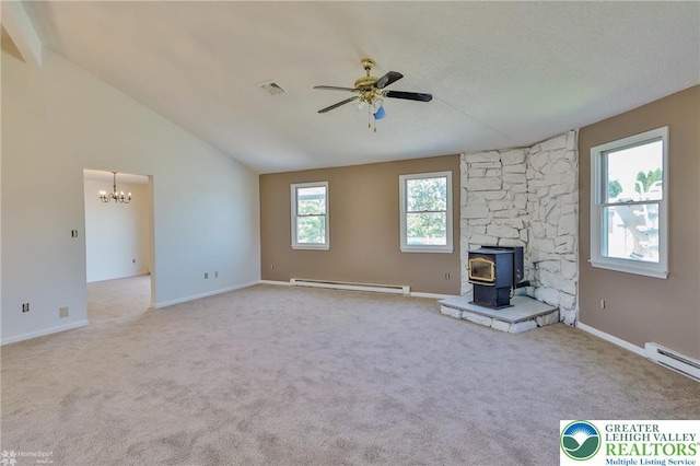 unfurnished living room featuring visible vents, a wood stove, lofted ceiling, a baseboard radiator, and ceiling fan with notable chandelier