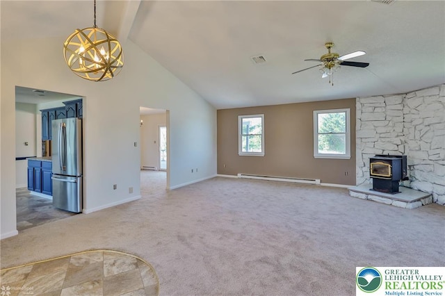 unfurnished living room featuring visible vents, a wood stove, ceiling fan with notable chandelier, a baseboard heating unit, and light carpet
